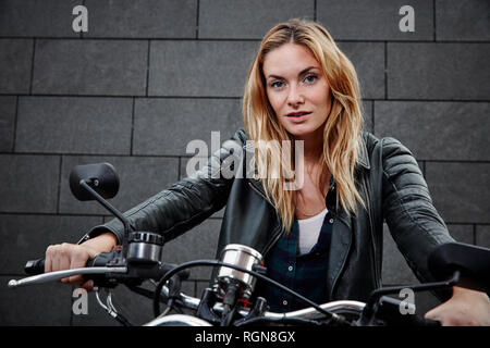 Portrait von selbstbewussten jungen Frau, die auf dem Motorrad Stockfoto