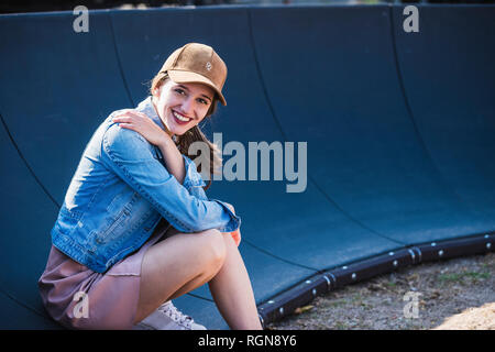 Portrait von lächelnden jungen Frau sitzt im Freien Stockfoto