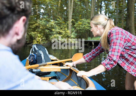Junge Frau ziehen Kanu auf einem Wald Bach mit Mann innerhalb Stockfoto