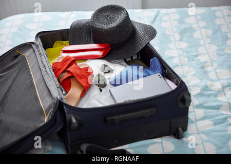 Koffer mit Sommer Urlaub Utensilien auf dem Bett Stockfoto