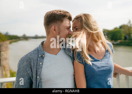 Liebevolle junge Paare auf einer Brücke über einen Fluss Stockfoto