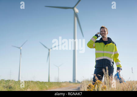 Lächelnd Ingenieur steht ein Feld an einem Windpark Gespräch am Handy Stockfoto