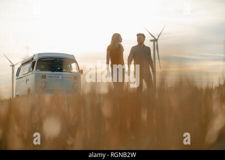 Junges Paar Hand in Hand auf Wohnmobil in ländlichen Landschaft bei Sonnenuntergang Stockfoto