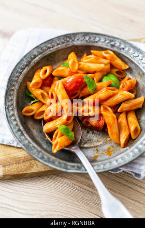 Penne mit Tomaten und Basilikum auf verzinnt Stockfoto