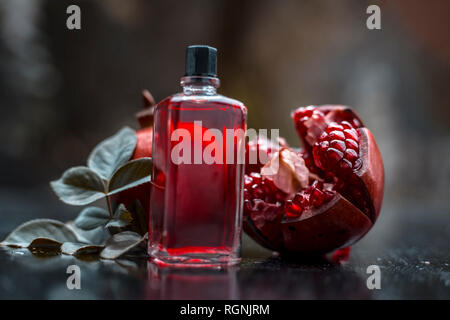 Nahaufnahme von ätherischen Öl der Granatapfel mit roh reif Granatapfel auf Holz- Oberfläche in transparente Flasche. Stockfoto