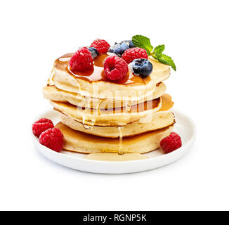 Leckere Pfannkuchen mit Beeren, Honig oder Ahornsirup. Hausgemachte Pfannkuchen und süße Sirup auf weiße Platte isoliert. Stockfoto