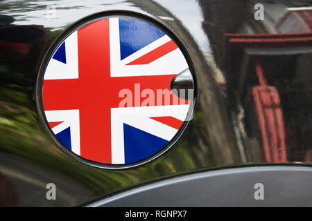 Nahaufnahme eines Runden tanken Kappe mit einer Gestaltung der nationalen Flagge von Großbritannien, durch schwarze glänzende auto Lack spiegelt die Umgebung umgeben Stockfoto