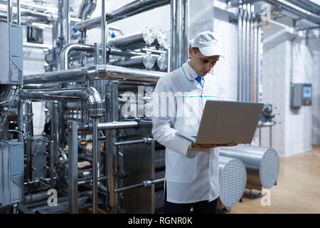 Techniker mit einem Laptop in der Hand an der Milchfabrik Stockfoto