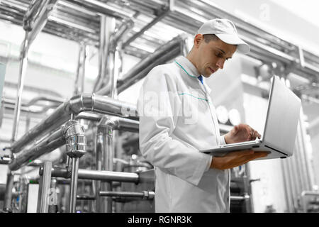 Techniker mit einem Laptop in der Hand an der Milchfabrik Stockfoto