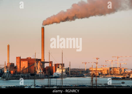 Helsinki, Finnland - 6. Dezember 2016: Sonnenuntergang am Abend Blick auf Industriegebiet von hanasaari Kraftwerk und Pier, Liegeplatz mit angelegten Schiffe, Schiffe. Stockfoto