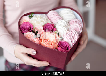 Rosa und weissen Marshmallows Geschenk und Blumen in Herzform mit weibliche Hände Stockfoto