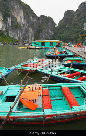 Ha Long Bay, Vietnam - 15. Dezember 2017. Holz- touristische Boote Warten auf Fahrgäste von der UNESCO in die Ha Long Bay an einem bewölkten Winter in niedrigen aufgeführten se Stockfoto
