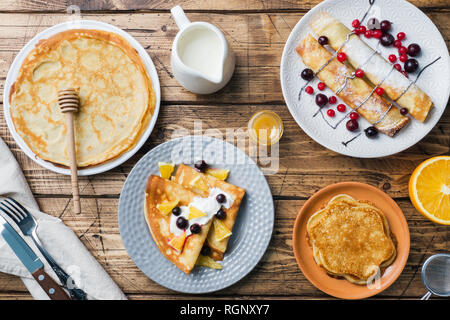 Verschiedene Arten von Pfannkuchen mit Beeren auf einem Holztisch. Stockfoto