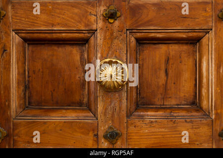 Vorderansicht eines Vintage Brown Holztür mit runden verzierten Messing Knopf Stockfoto