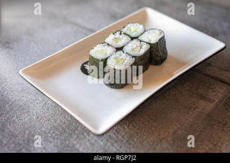 Gurke Sushi serviert auf Rechteckige weiße Platte auf dunklen grauen Stein Hintergrund Stockfoto