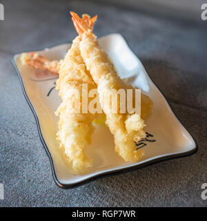 Tempura Garnelen serviert auf Rechteckige weiße Platte auf dunklen grauen Stein Hintergrund Stockfoto