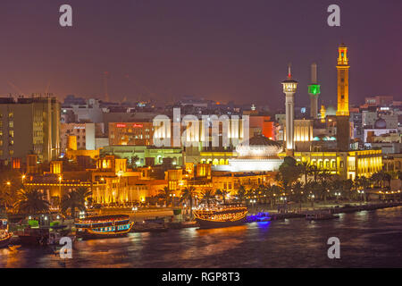 Bastikiya, der alte Kaufmann Viertel von Dubai, direkt neben dem Dubai Creek in der Nacht. Beleuchtete Restaurant daus stehen im Vordergrund. Stockfoto