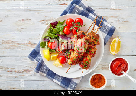Chicken Döner Spezialitäten vom Holzkohlegrill auf Spieße mit Salat, Zitrone Keile auf einer weißen Platte, auf einem Holztisch, Ansicht von oben, flatlay Stockfoto