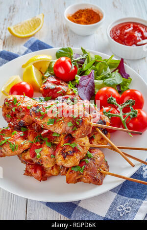 Appetitlich chicken Döner Spezialitäten vom Holzkohlegrill auf Spieße mit Kräutern Salat, Tomaten, Zitrone Keile auf einer weißen Platte, auf einer hölzernen Tabelle, Ansicht von oben Stockfoto