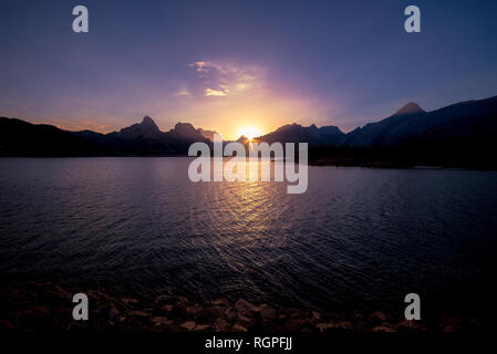 Tolle Aussicht auf Wasseroberfläche zwischen hohen Bergen und blauem Himmel bei Sonnenaufgang Stockfoto