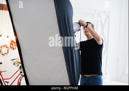 Fotograf passt das Blitzlicht auf Studio. Stockfoto