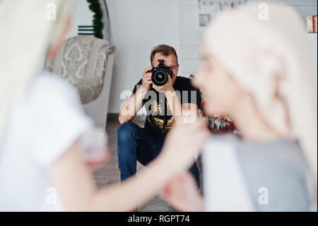 Mann Fotograf Shooting im Studio zwei Mädchen, während sie ihre eigenen Masken Creme machen. Professioneller Fotograf auf der Arbeit. Stockfoto