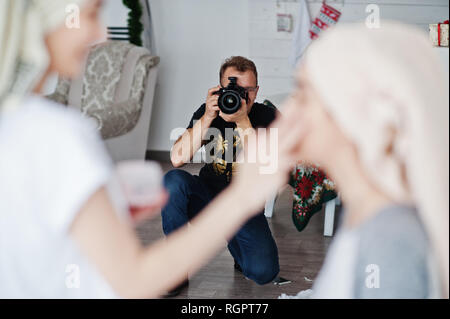 Mann Fotograf Shooting im Studio zwei Mädchen, während sie ihre eigenen Masken Creme machen. Professioneller Fotograf auf der Arbeit. Stockfoto