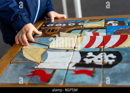 Die Hände des Kindes ausfüllen ein Handwerker Puzzle aus Holz Würfel. Stockfoto