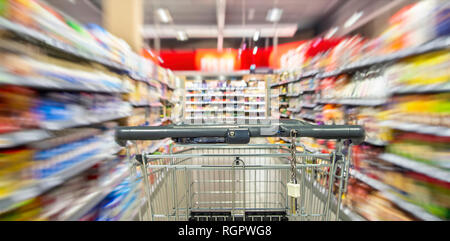 Ein leerer Warenkorb zwischen Regal Zeilen in den Supermarkt mit Bewegungsunschärfe. Stockfoto