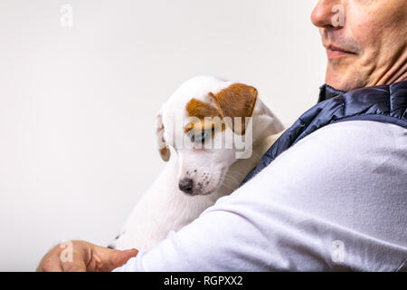 Horizontale Portrait von Stattlichen fröhliche Mann hält Jack Russell terrirer, hat mich Ausdruck Stockfoto