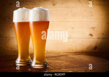 Zwei Ice cold Gläser schaumigen größer oder Weizen Bier auf einem urigen Theke mit seitlichen Vignette und Kopie Raum Stockfoto