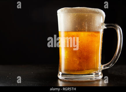 Großes Glas mug Brausetabletten gekühlt glitter Bier mit einem guten schaumigen Kopf über einer reflektierenden schwarzen Hintergrund mit Kopie Raum Stockfoto