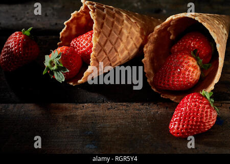 Nahaufnahme der Erdbeeren in knuspriger Waffel Lagerinnenringe gegen Holz- Hintergrund Stockfoto