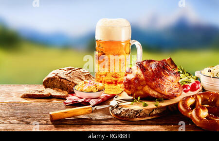 Traditionelle deutsche Küche, Schweinshaxe gebraten ham Hock, Brezel mit obatzter Schmelzkäse und Glas in hellem Bier auf hölzernen Tisch Stockfoto