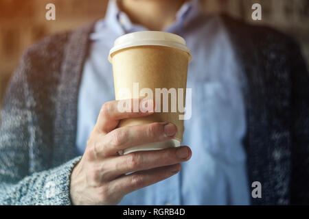 Büro eine Tasse Kaffee. Kaffeepause Hand Pappbecher Strickjacke blaues Hemd. Kaffeepause Konzept Stockfoto