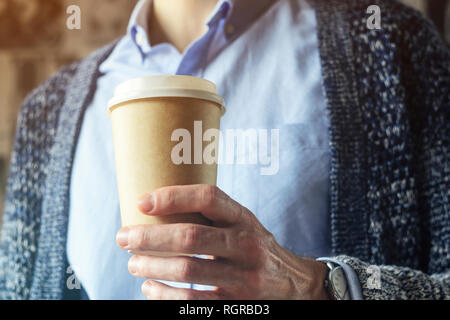 Büro eine Tasse Kaffee. Kaffeepause Hand Pappbecher Strickjacke blaues Hemd. Kaffeepause Konzept Stockfoto
