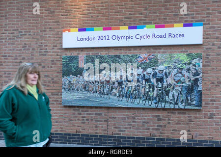 Frau vorbei gehen. ein Bild (Artwork) der London 2012 olympischen Zyklus Straße Rennen in Woking, Surrey, Großbritannien Stockfoto