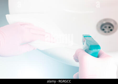 Eine Frau wäscht ihr rosa Handschuhe mit einem weißen Waschbecken und Wasserhahn im Bad zu Hause mit Servietten und Spray. Hausaufgaben Vergnügen Stockfoto