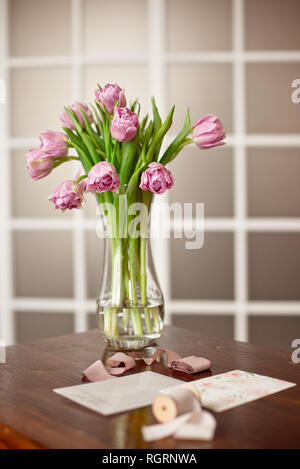 Lavendel Lila Blüten in einem goldenen Vase auf einem hölzernen Tisch in einem eleganten Interieur mit Grußkarten und eine samt Box mit Dekoration Stockfoto