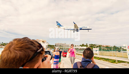 Philipsburg, Sint Maarten - Januar 24, 2016: Urlaub auf Maho Beach an der Karibik. Ebene niedrig fliegen über Menschen. Jet Flug Land an bewölkten Himmel. Flugzeug im sonnigen Wolken. Fernweh, Reisen und Reise. Stockfoto