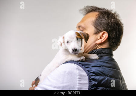 Horizontale Portrait von Stattlichen fröhliche Mann hält Jack Russell terrirer, hat mich Ausdruck Stockfoto