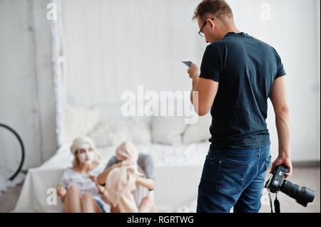 Mann Fotograf Shooting im Studio zwei Mädchen, während sie ihre eigenen Masken Creme machen. Professioneller Fotograf auf der Arbeit und Telefon für Tipps. Stockfoto