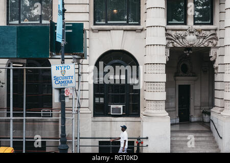 New York - Juni 1, 2018: Afrikanische amerikanische Mann zu Fuß von nypd Kameras Zeichen in Manhattan, New York. Neue nypd Überwachungskameras haben in 20 hinzugefügt. Stockfoto