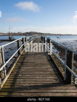 Hölzerne Seebrücke, die zu Segelboote im Hafen bei Ebbe Stockfoto