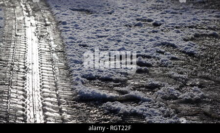 Reifen Tread Marks im Schnee Aufdruck auf einer vereisten Straße im Winter. Stockfoto