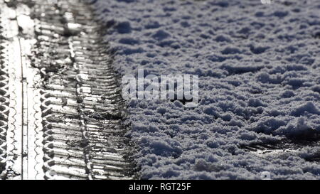 Reifen Tread Marks im Schnee Aufdruck auf einer vereisten Straße im Winter. Stockfoto