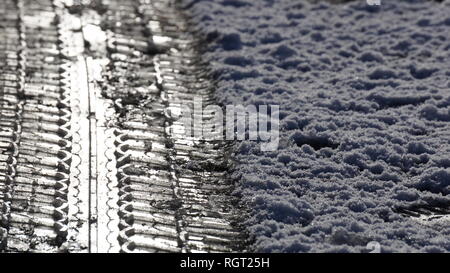 Reifen Tread Marks im Schnee Aufdruck auf einer vereisten Straße im Winter. Stockfoto