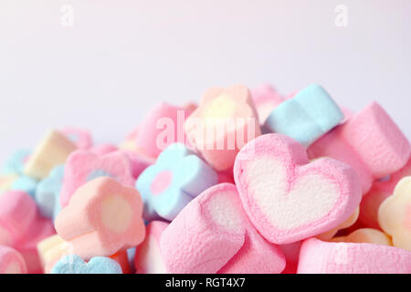 Geschlossen bis ein rosa und weißen Herzförmigen Marshmallow auf dem Stapel von Pastell Farben Blumen geformte Marshmallow Bonbons, Valentine Karte Stockfoto