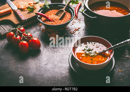 Gesund vegan Linsensuppe in der Schüssel mit Löffel auf dunklen Küche Tisch Hintergrund mit Zutaten. Vegetarisches Essen. Saubere Diät essen. Quelle der Anlage ba Stockfoto