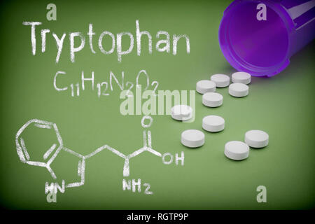 Pillen Verschütten von einer geöffneten Flasche auf grünem Hintergrund, chemischen Formulierung von Trytophan mit Kreide geschrieben, konzeptionelle Bild Stockfoto